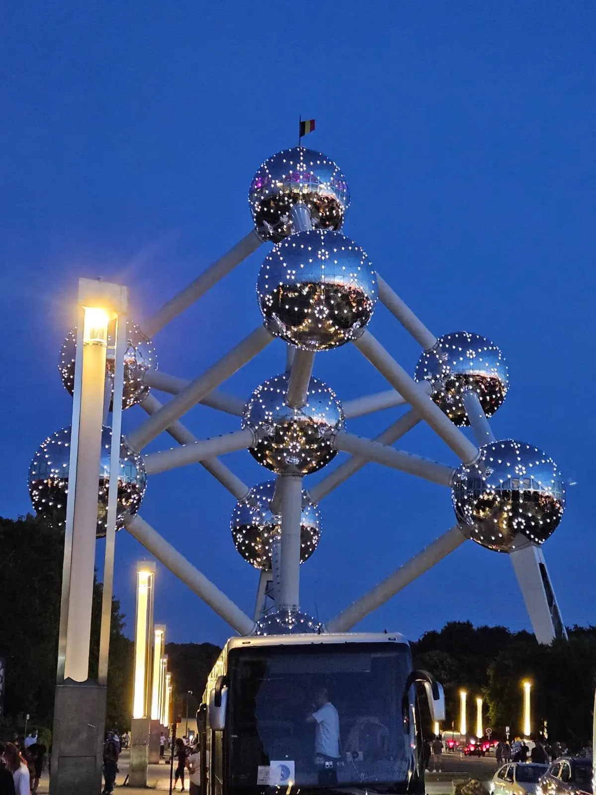 Reisebus vor dem abends beleuchteten Atomium in Brüssel