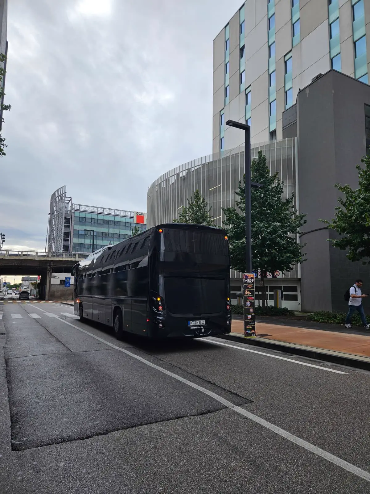 Schwarzer Reisebus von hinten auf einer Stadtstraße, am Heck steht Mikanovic.de