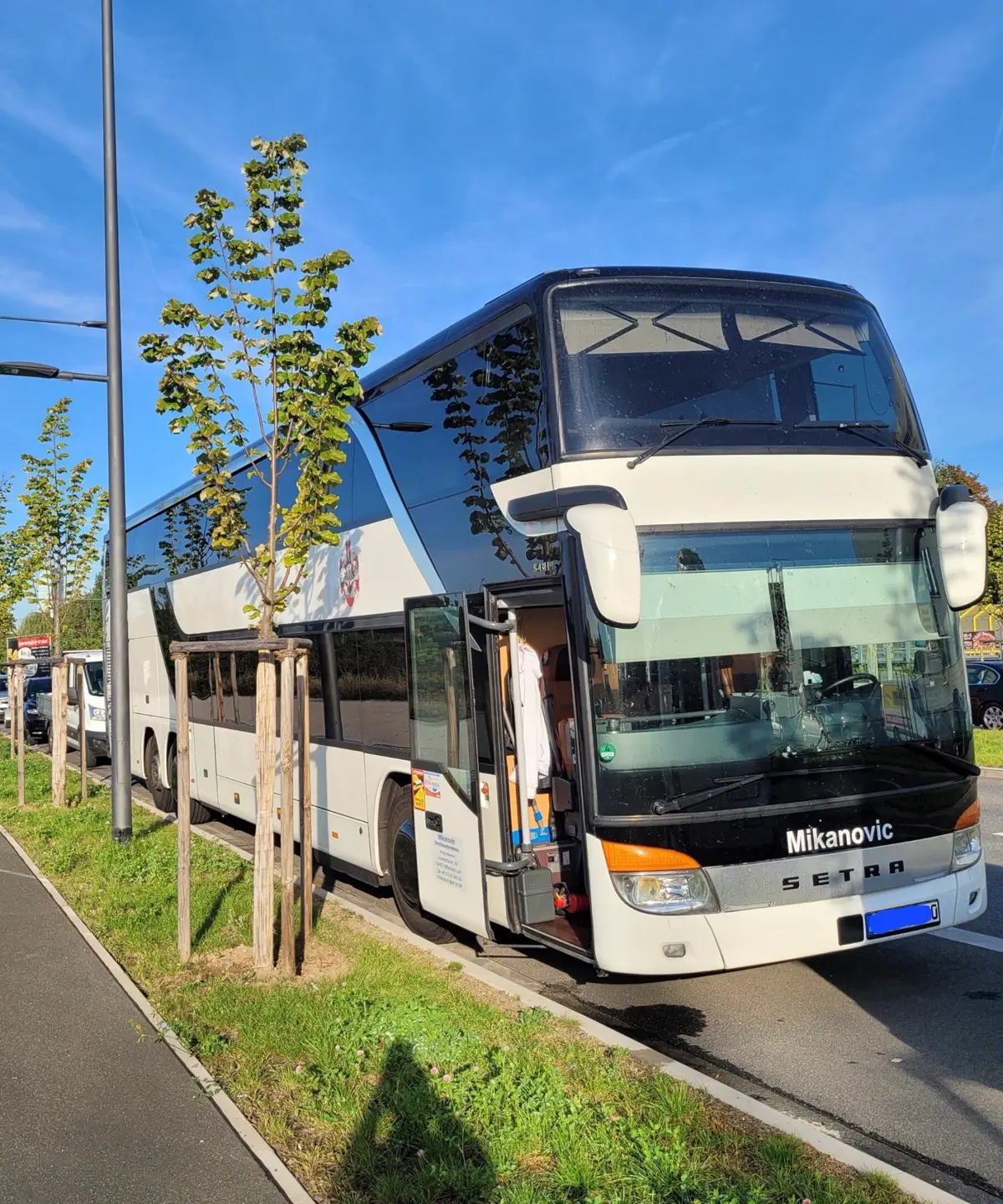 Weißer Setra-Doppeldeckerbus von Mikanovic mit geöffneter Einstiegstür am Straßenrand