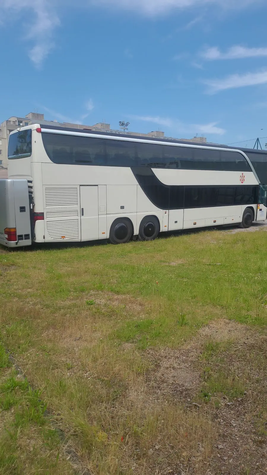 Weißer Doppeldecker-Reisebus, Seitenansicht von hinten, unter blauem Himmel